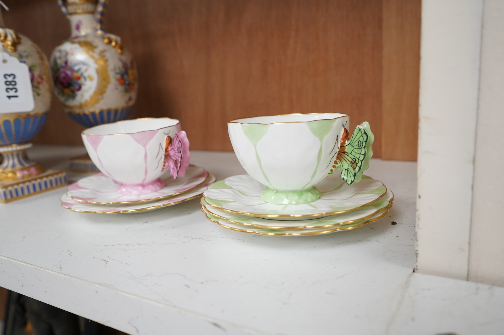 Two Aynsley trios with butterfly handles and one extra saucer, numbered 785788